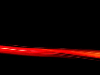 One ribbon of red light stretches across the lower third of the frame, blurred at both ends with pure black above it.