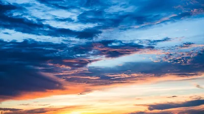 A dark navy cloud shelf presses down from the top while gold-lit clouds burn along the bottom edge, the fiercest colour kept low in the frame.