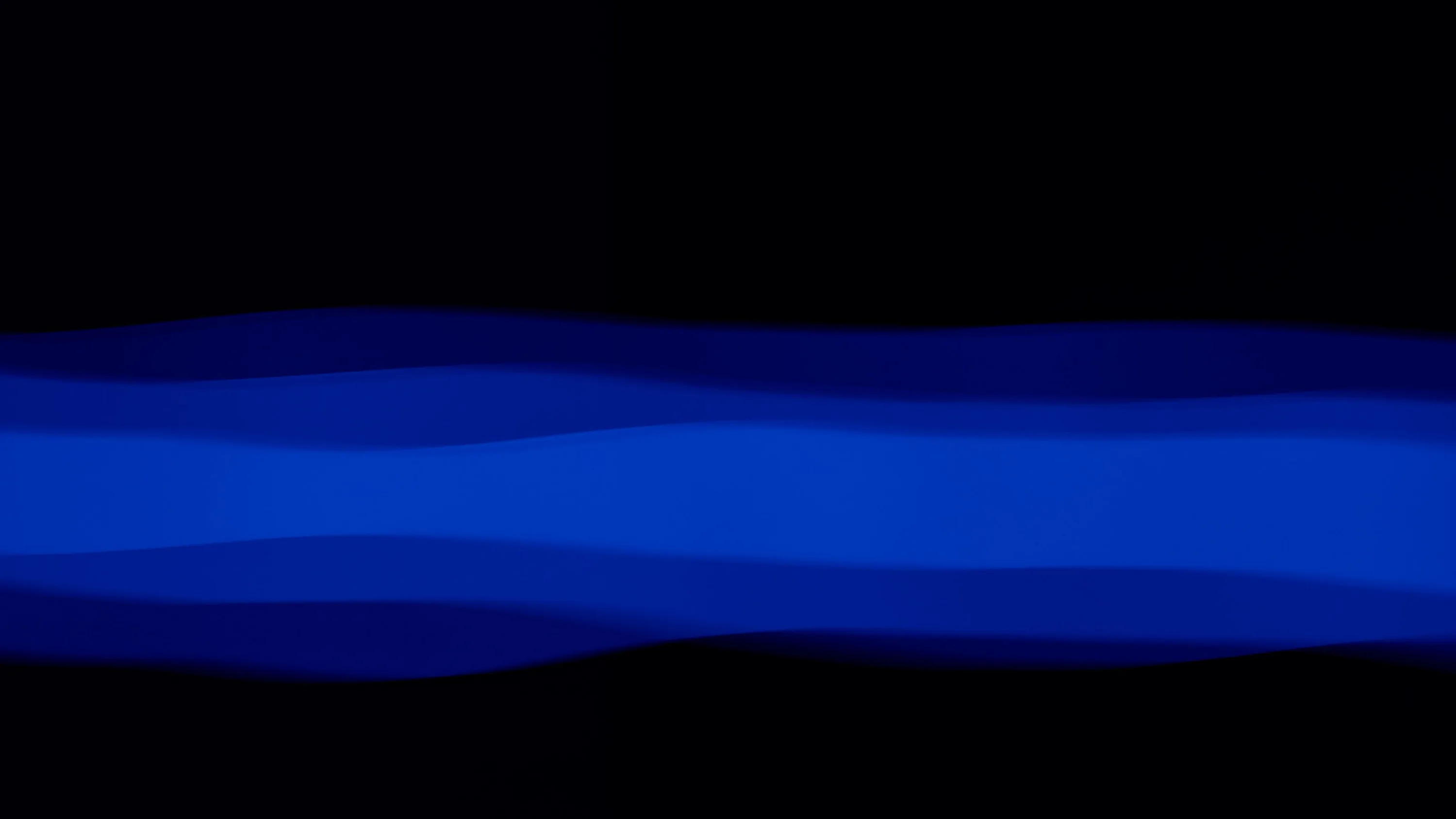 A single band of layered cobalt waves runs the full width of the frame, everything above and below it dropping to solid black.