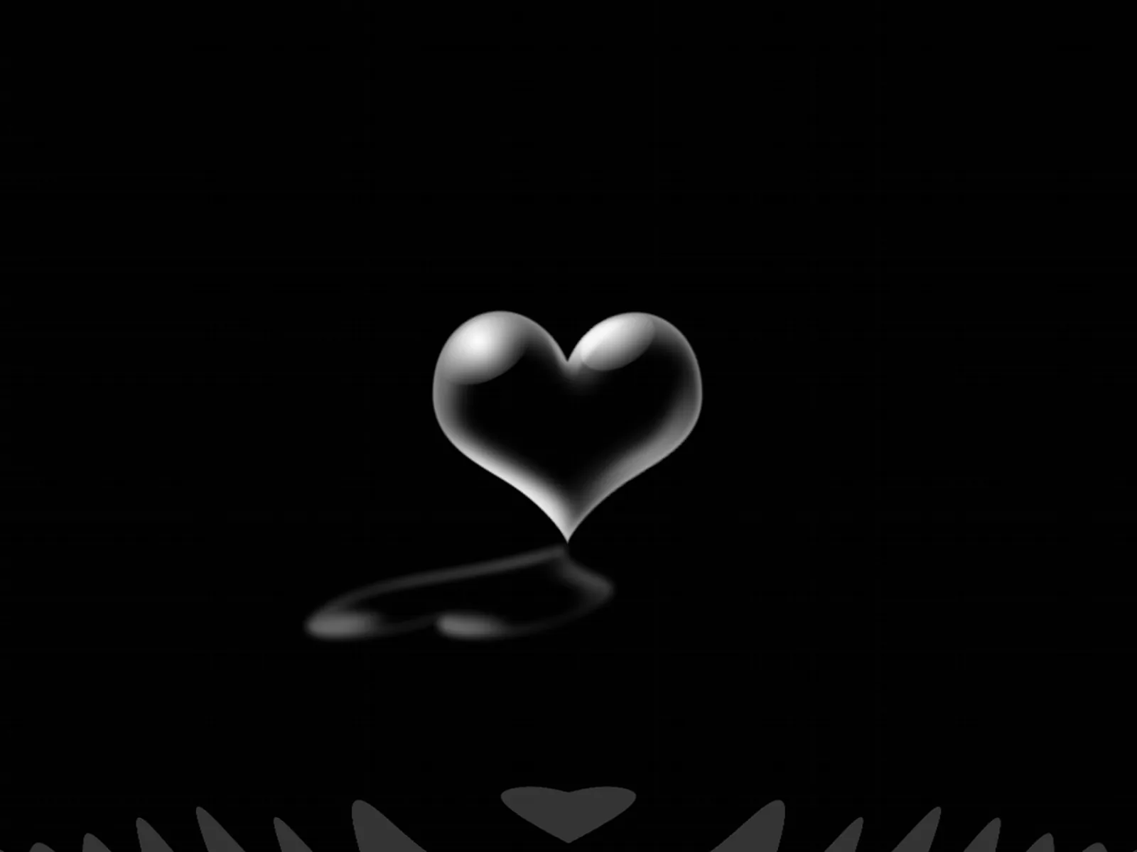A smooth chrome heart hovers just above a black glossy surface, one highlight running down its left lobe and a soft reflection beneath.