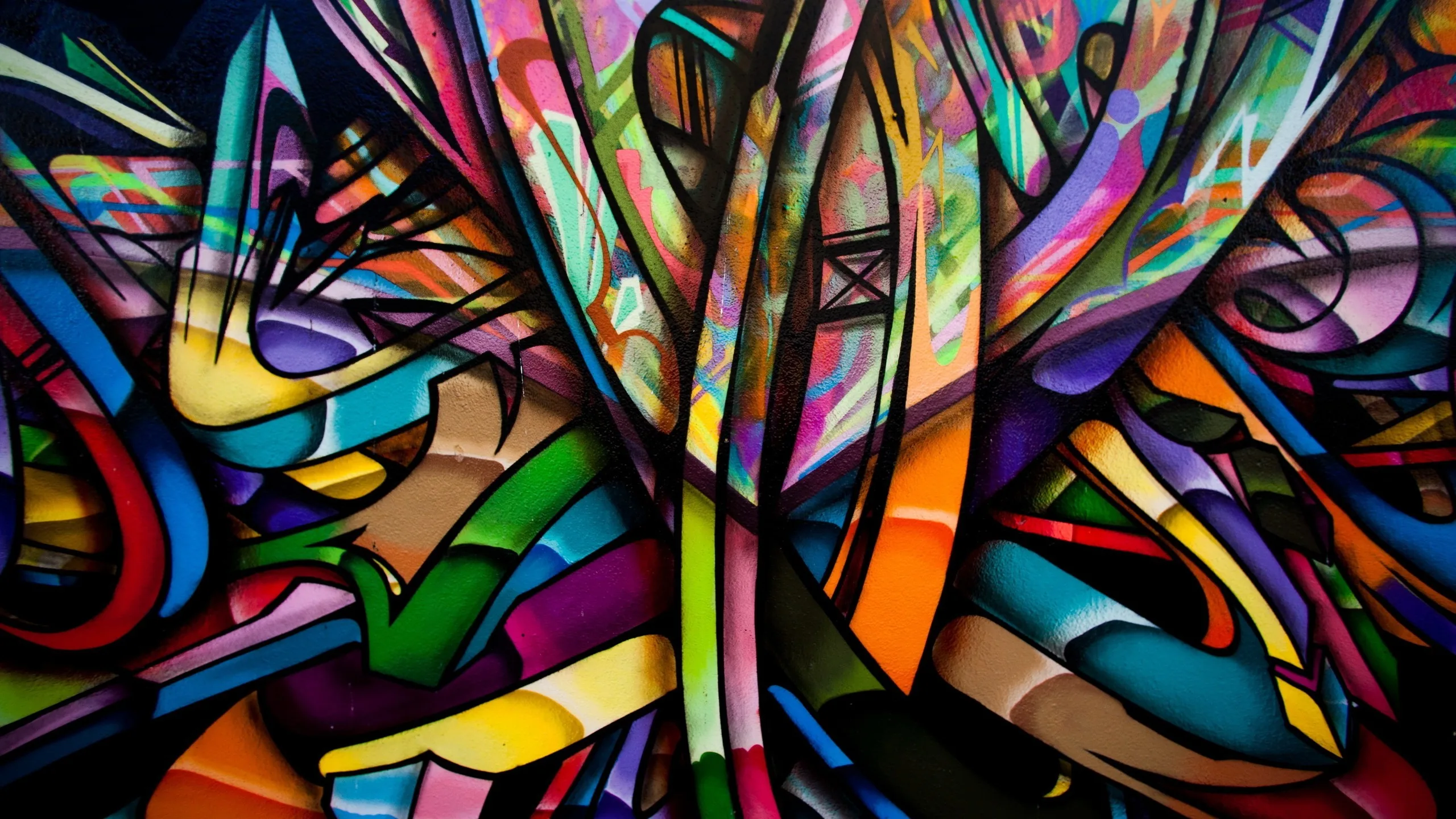 Interlocking spray-paint shapes in pink, teal, purple, and lime pack the wall edge to edge in wildstyle graffiti, busiest right at the centre.
