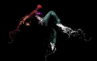 A break-dancer frozen mid-move, the body dissolving into red and white splashes of liquid on a completely black field.