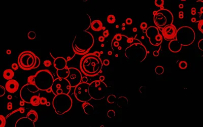 Red rings of different sizes drift diagonally across black, clustering thickly at the lower left and thinning out towards the top right.