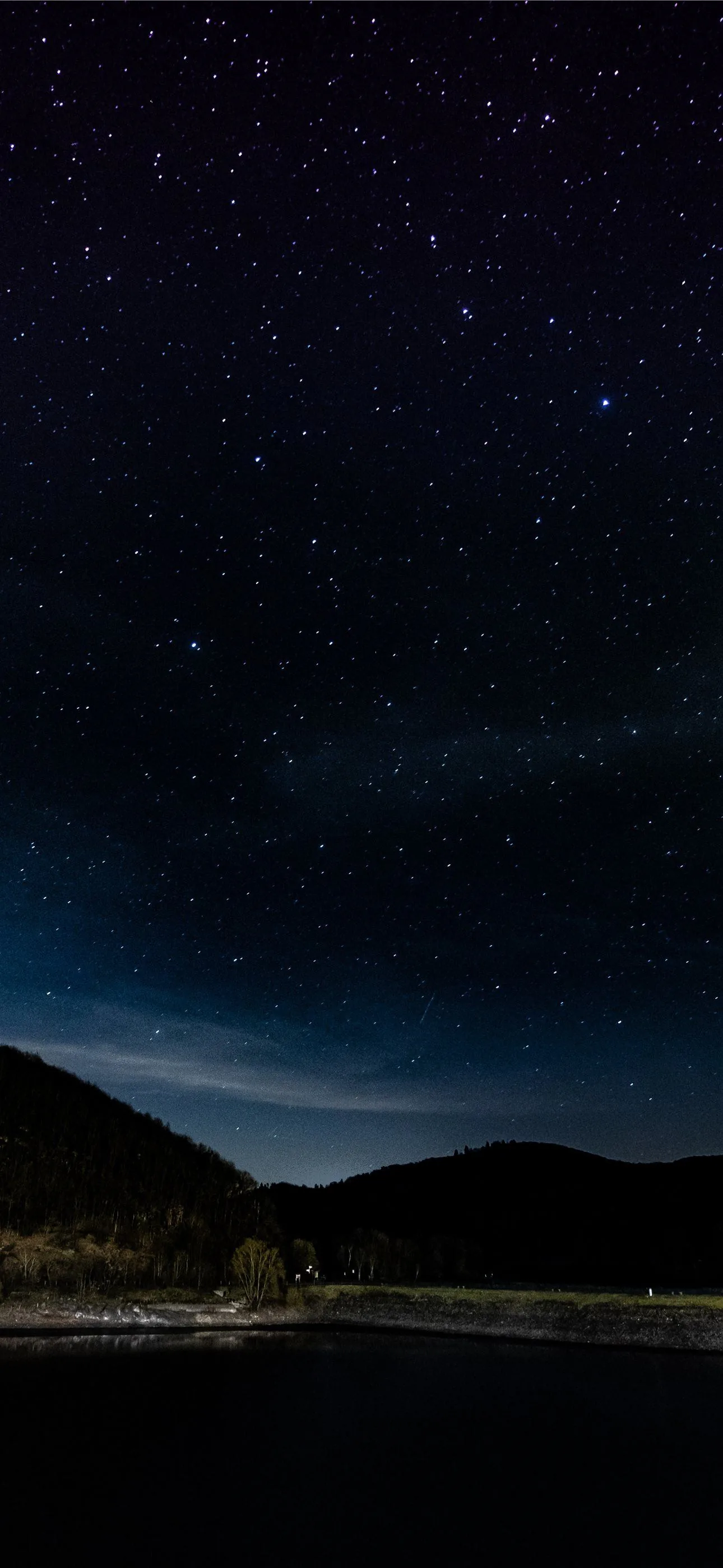 Sparse stars over black hills and still water in this tall frame — the bottom third is almost pure black, handy for phone dock icons.