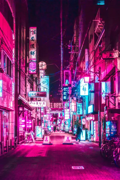 Vertical signs and lanterns wash a narrow Japanese alley in pink and cyan, traffic cones on the wet street and the sky above fading to black for the status bar.