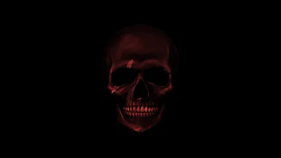 Deep red light rakes across a skull from the front, the jaw and eye sockets sinking into black with nothing else in the frame.