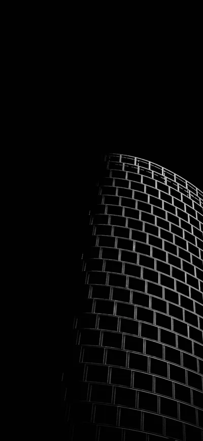 The curved brick face of a tall building catches a thin sidelight along its edge while the left half of the frame stays completely black.