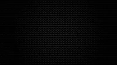 A tight diagonal carbon weave covers the frame, catching a dim light from the upper left so the pattern reads only in the highlights.