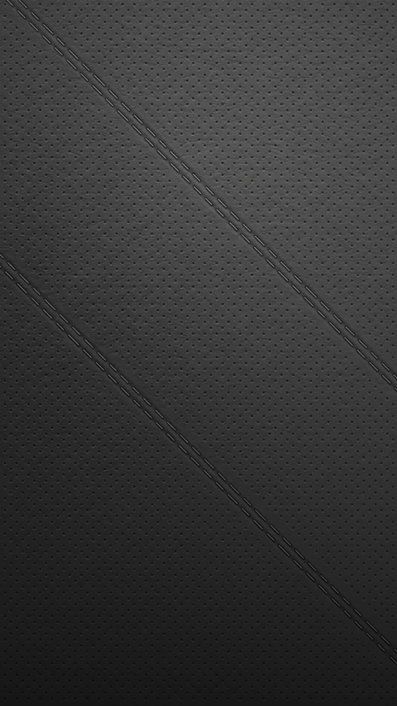 A fine diamond-quilted grain covers a charcoal surface, cut by two stitched diagonals that run from the top left corner down to the right edge.