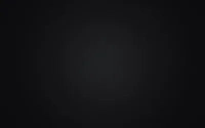 A soft grey glow sits at the centre of a seamless studio backdrop and falls off evenly to black in every corner.
