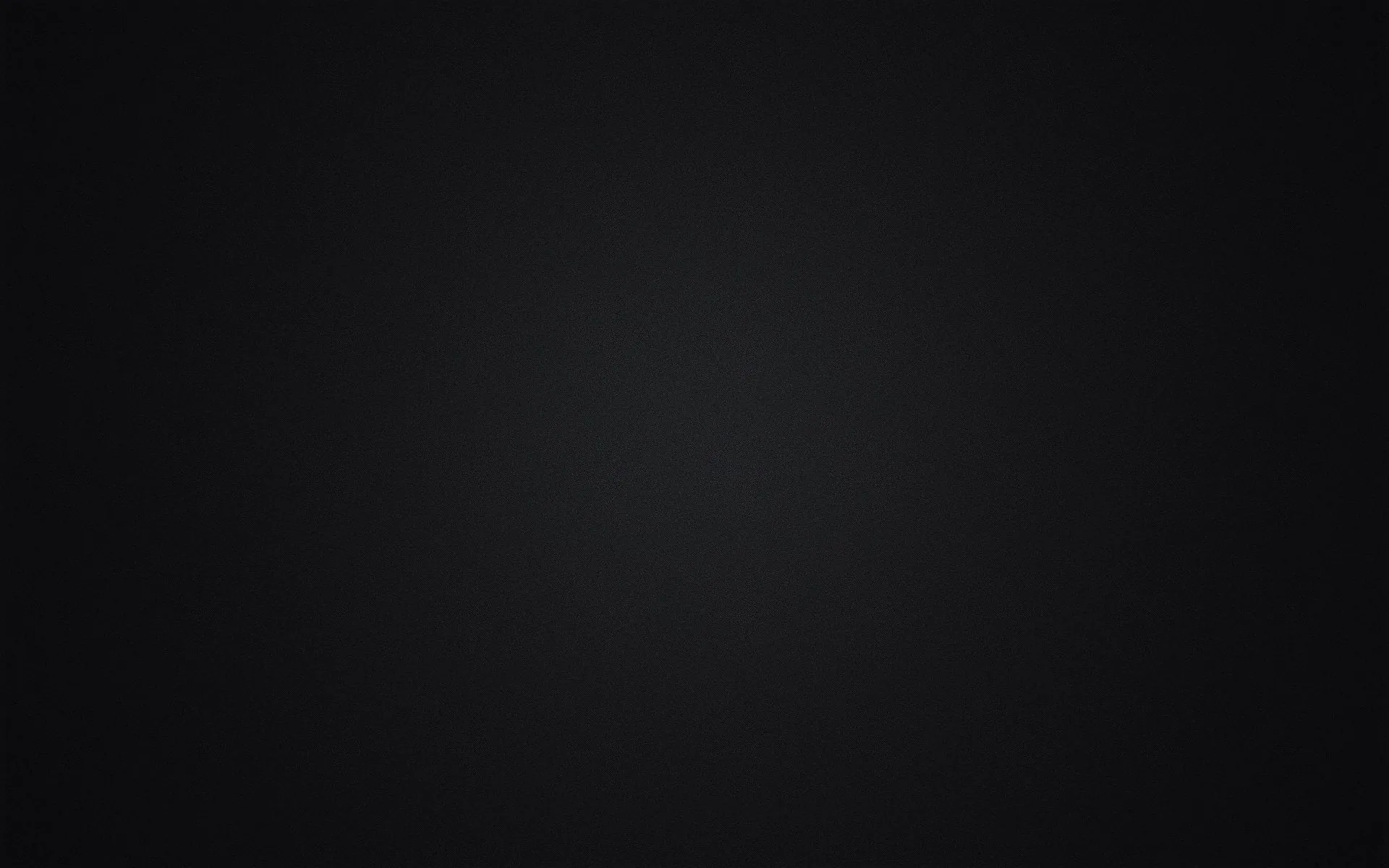 A soft grey glow sits at the centre of a seamless studio backdrop and falls off evenly to black in every corner.