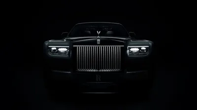 The saloon faces the camera on a black background, chrome vanes of the grille and the two slim LED headlamps carrying almost all of the light in the frame.