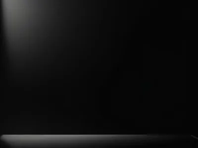 A single soft glow falls down the upper left of a black studio wall, the floor line running straight across the bottom and the right side staying in shadow.