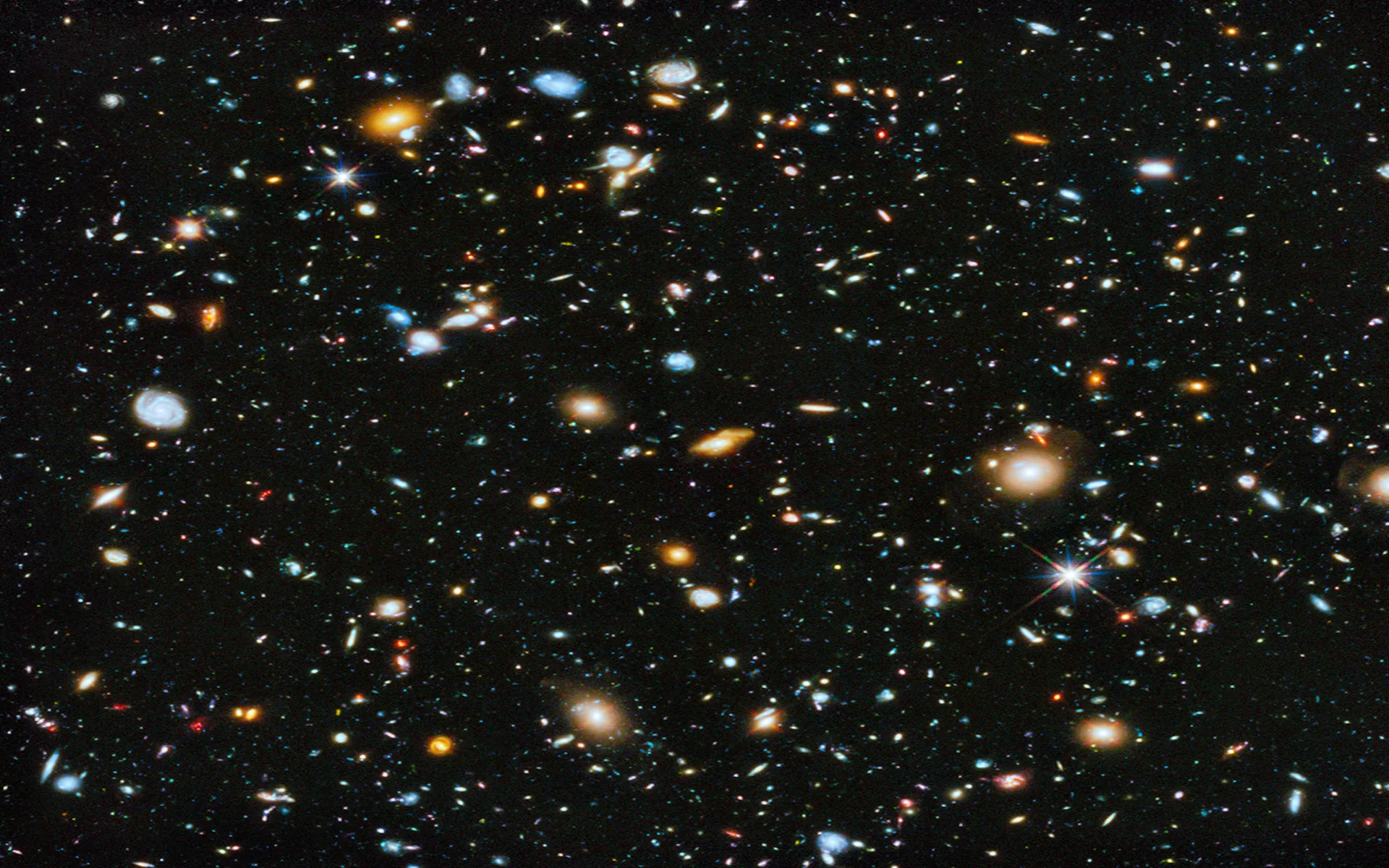 Thousands of distant galaxies scattered across a black frame in the style of a Hubble deep-field shot, with no single subject to fight your desktop icons.