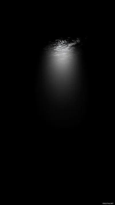 One beam falls onto rippling water at the top of the frame, the glow fading out well before the bottom edge.