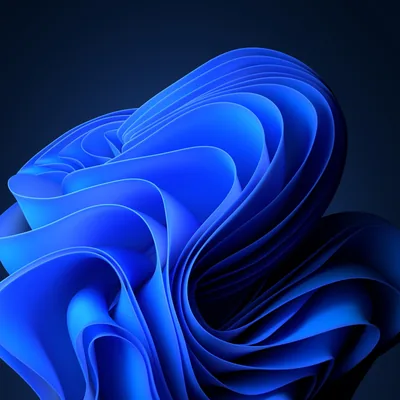 Folded ribbons of cobalt blue curl outward like petals against a deep navy background, the folds brightest at the centre of the bloom.