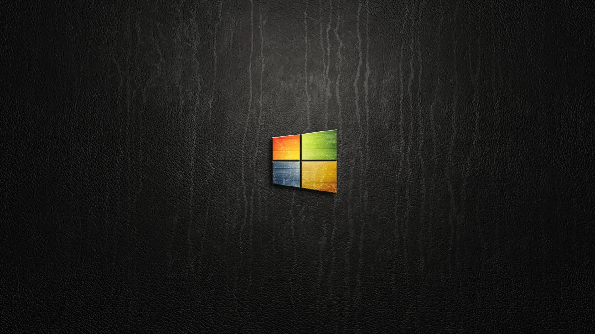 The four coloured panes glow in the middle of a scratched charcoal wall, the only colour against the grey vertical streaks around it.