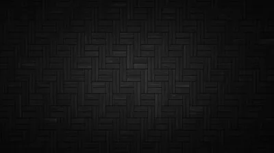 Rectangular tiles laid in a herringbone weave across a dark surface, lit through the middle so the corners drop away.