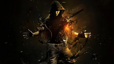 A masked man in a hoodie spreads his arms as his torso breaks into flying debris, orange embers at the core, the surrounding frame falling to near black.
