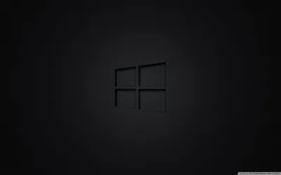The four-pane Windows mark sits small and unlit at the centre of an even charcoal wall.