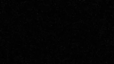 Fine pale specks scatter unevenly across solid black like distant stars or film grain, thinning out toward the bottom of the frame.
