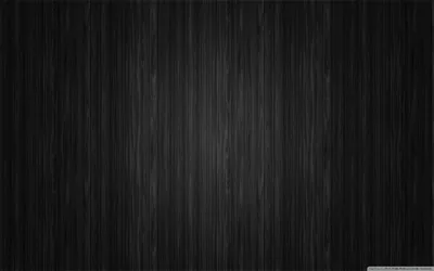 Close-up vertical grain running the full height of a near-black surface, a faint sheen down the centre and the sides in shadow.