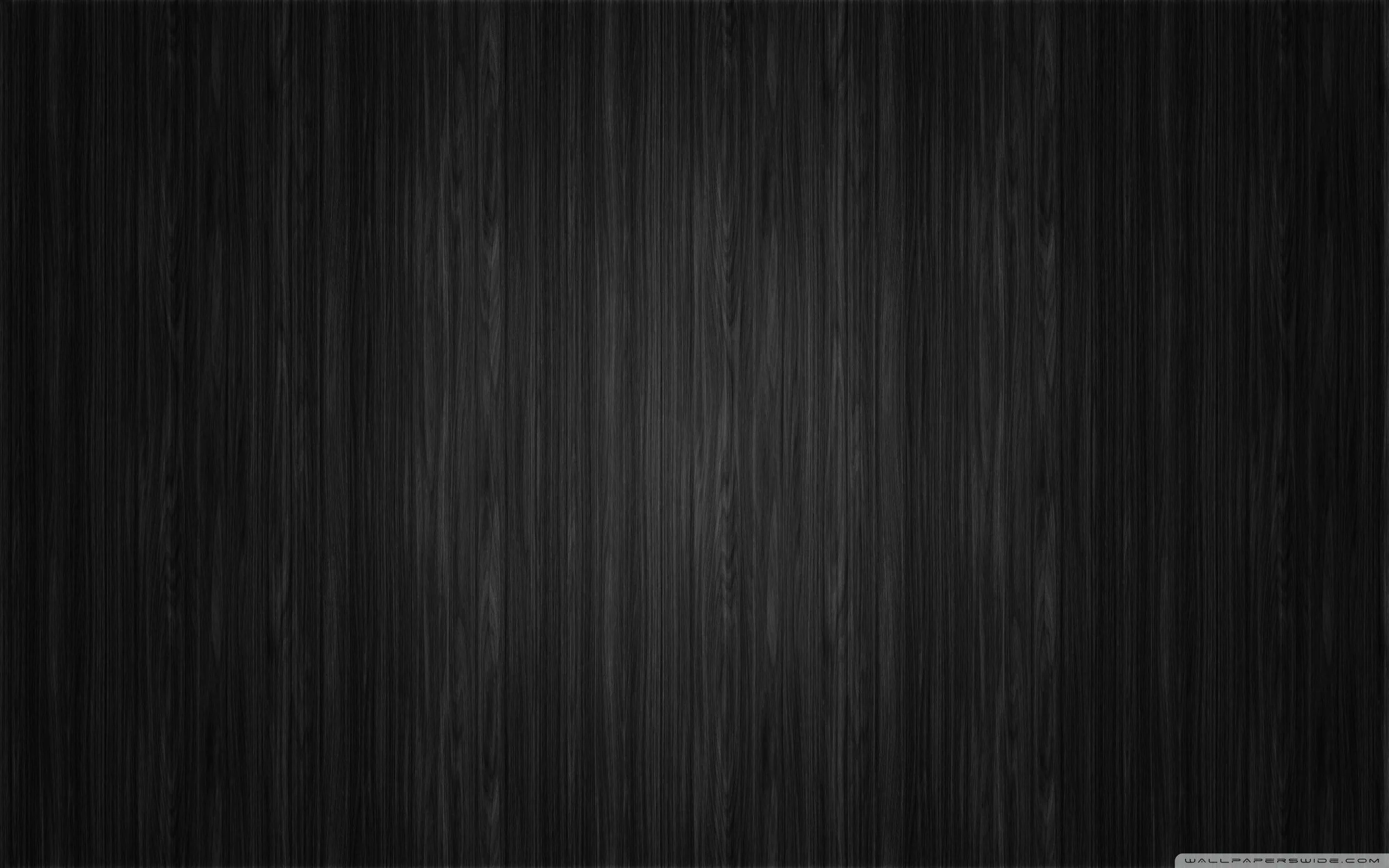 Close-up vertical grain running the full height of a near-black surface, a faint sheen down the centre and the sides in shadow.