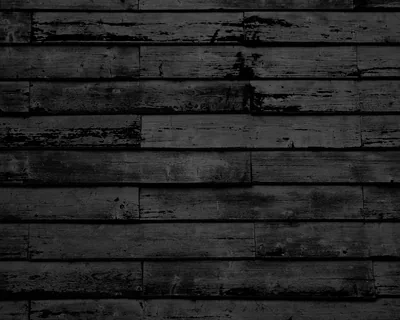 Horizontal boards under flaking black paint, bare grey grain showing through most heavily left of centre, with tight dark seams dividing every plank.