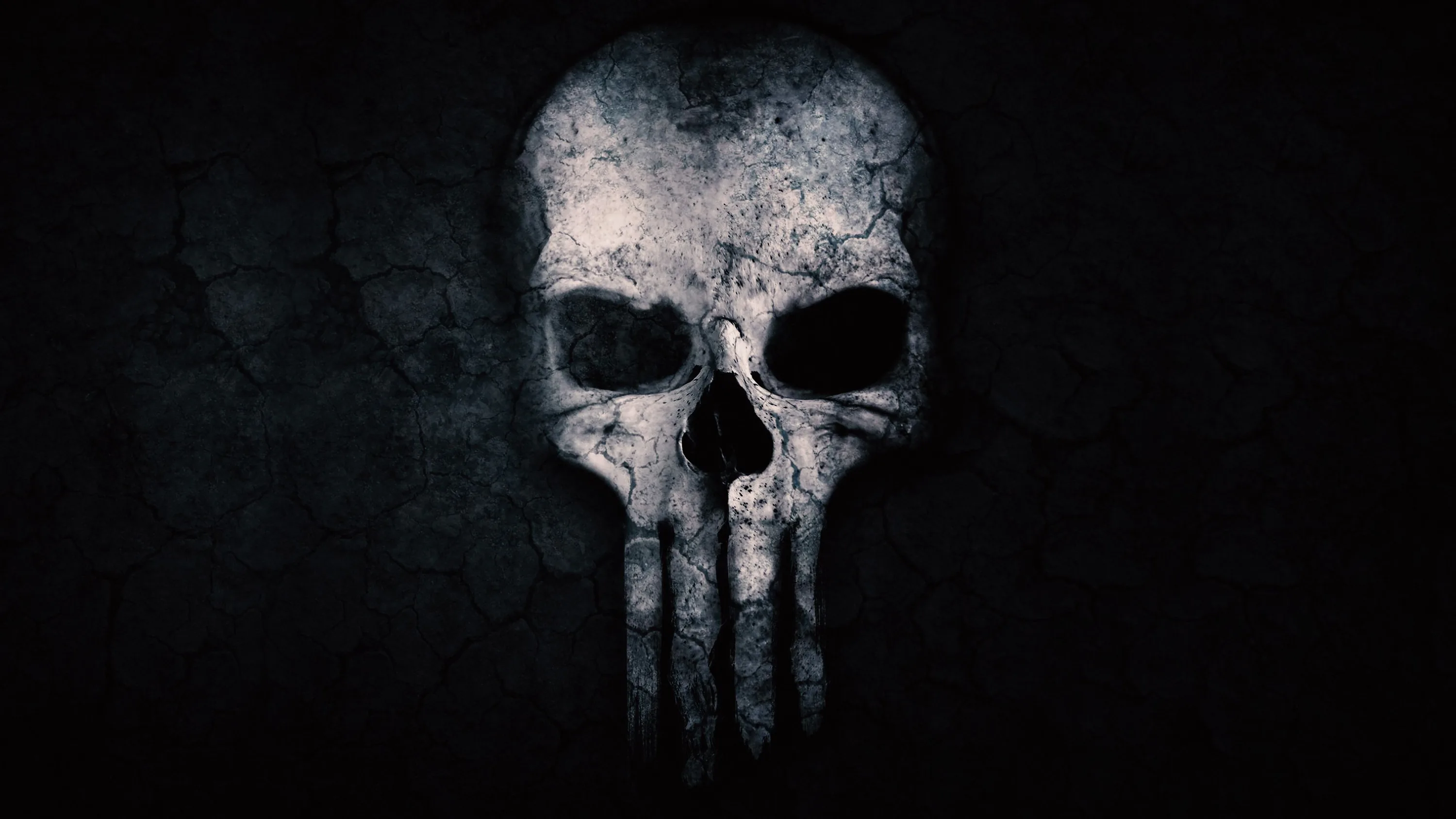 A cracked, dusty skull with four long teeth looms out of black, lit from above so the eye sockets stay in shadow.