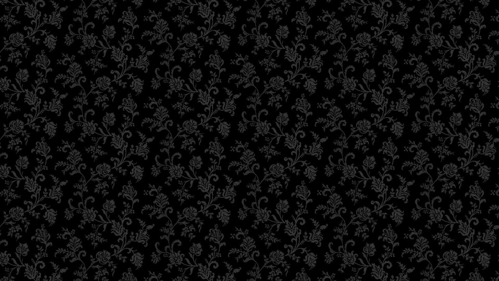A repeating floral damask sits barely a shade above the black ground, visible only where the light catches the raised print.