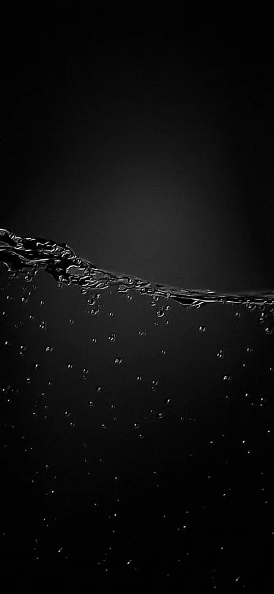 The waterline runs across the upper third with small bubbles clinging under it, the rest of the frame fading into black.