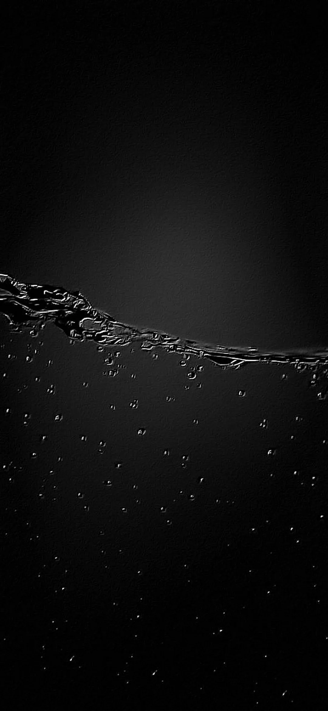 The waterline runs across the upper third with small bubbles clinging under it, the rest of the frame fading into black.