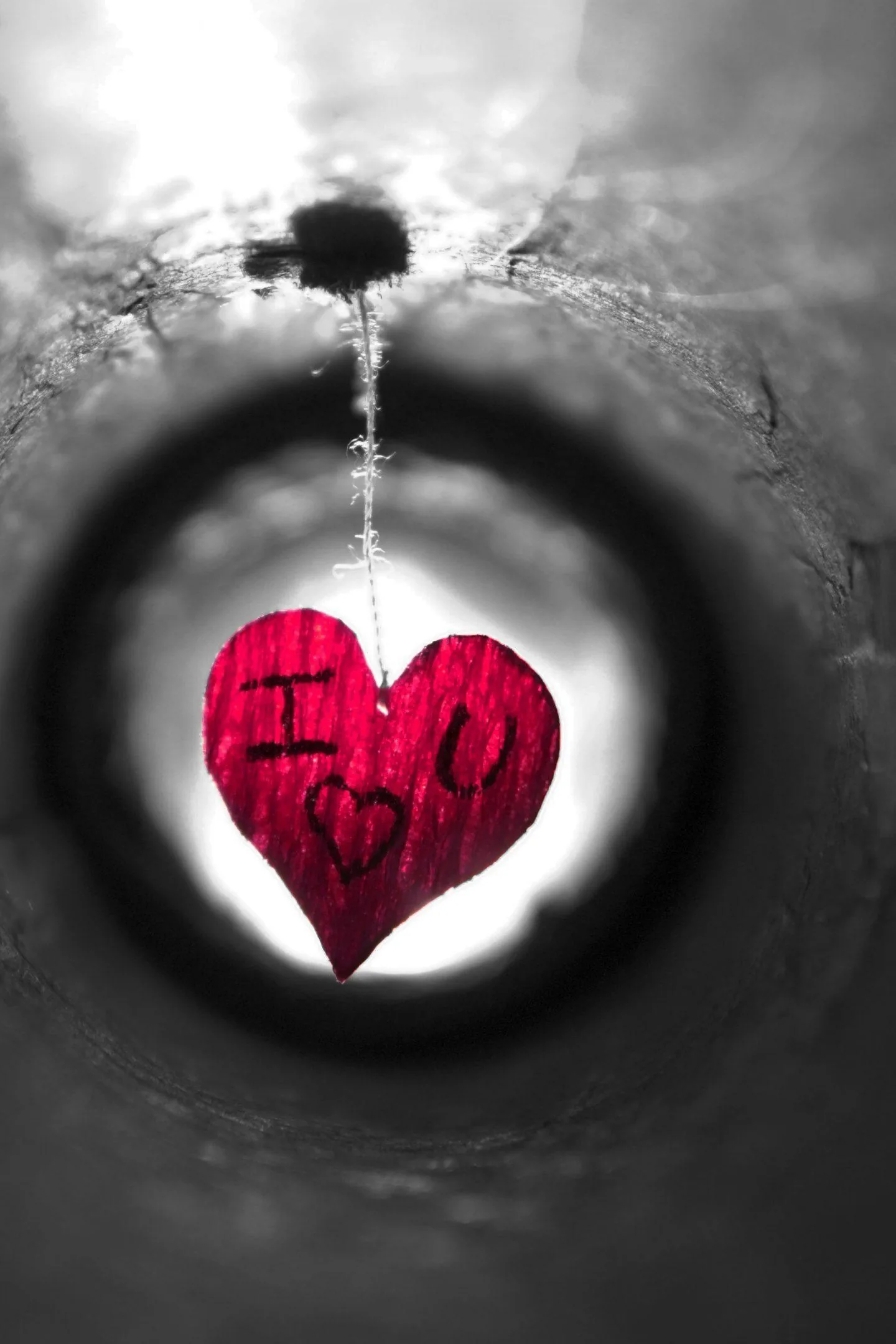 A red heart painted at the end of a concrete pipe, the ring of tunnel wall around it left in grey monochrome.
