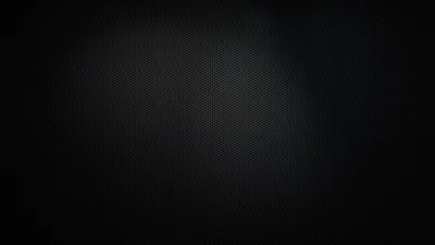 A tight carbon mesh weave covers the whole surface, a faint pool of light at the centre and the border sinking to black.