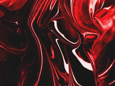 Poured red and black paint folds into thick glossy ridges, the light catching each crest where the two colours pull apart.