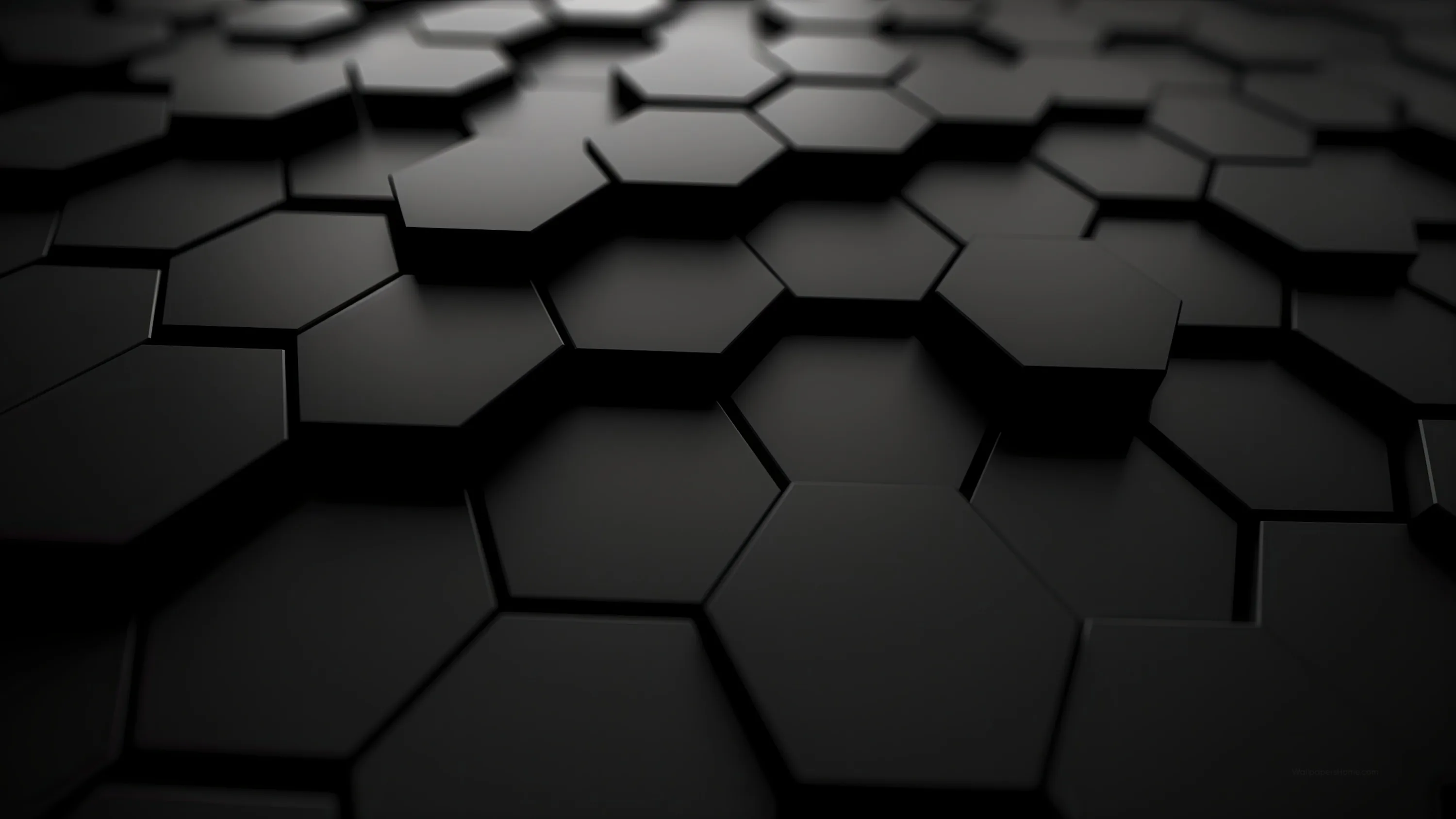 Matte black hexagons sit at slightly different heights, their edges picking up a low raking light.
