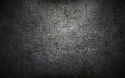 A worn grey surface covered in fine scratches and small pits, a heavy vignette pulling all four corners down to near black.