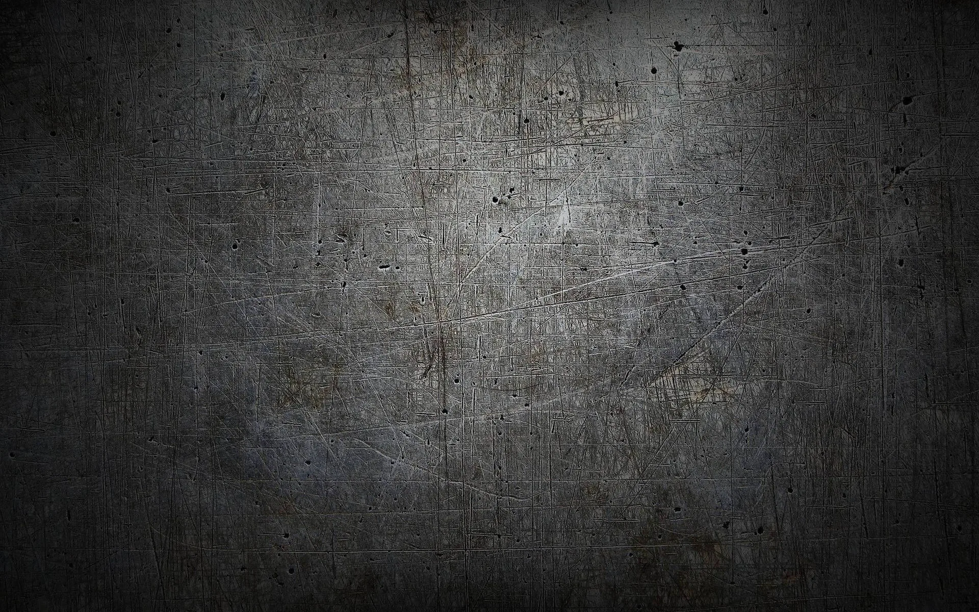 A worn grey surface covered in fine scratches and small pits, a heavy vignette pulling all four corners down to near black.