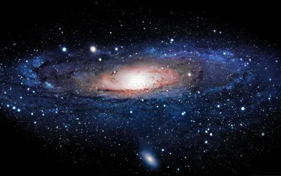 A wide spiral galaxy fills the frame with blue arms and a white core, a tiny companion galaxy hanging just beneath its lower rim.
