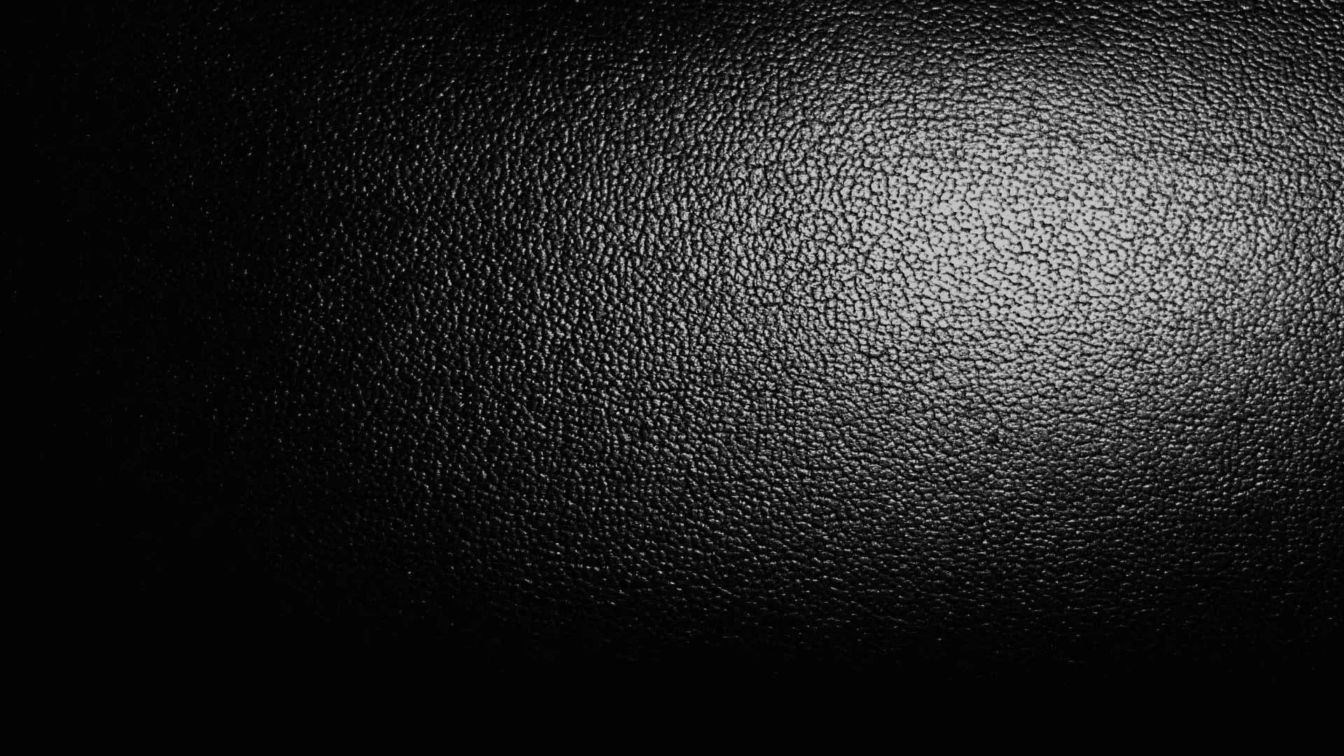 A pebbled grey-black surface catches a wide pool of light on the right, the left third of the frame left completely dark.