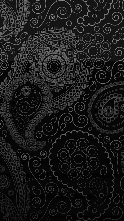 Paisley teardrops and spiral rosettes are pressed into a black surface, the raised outlines catching just enough light to separate them from the background.