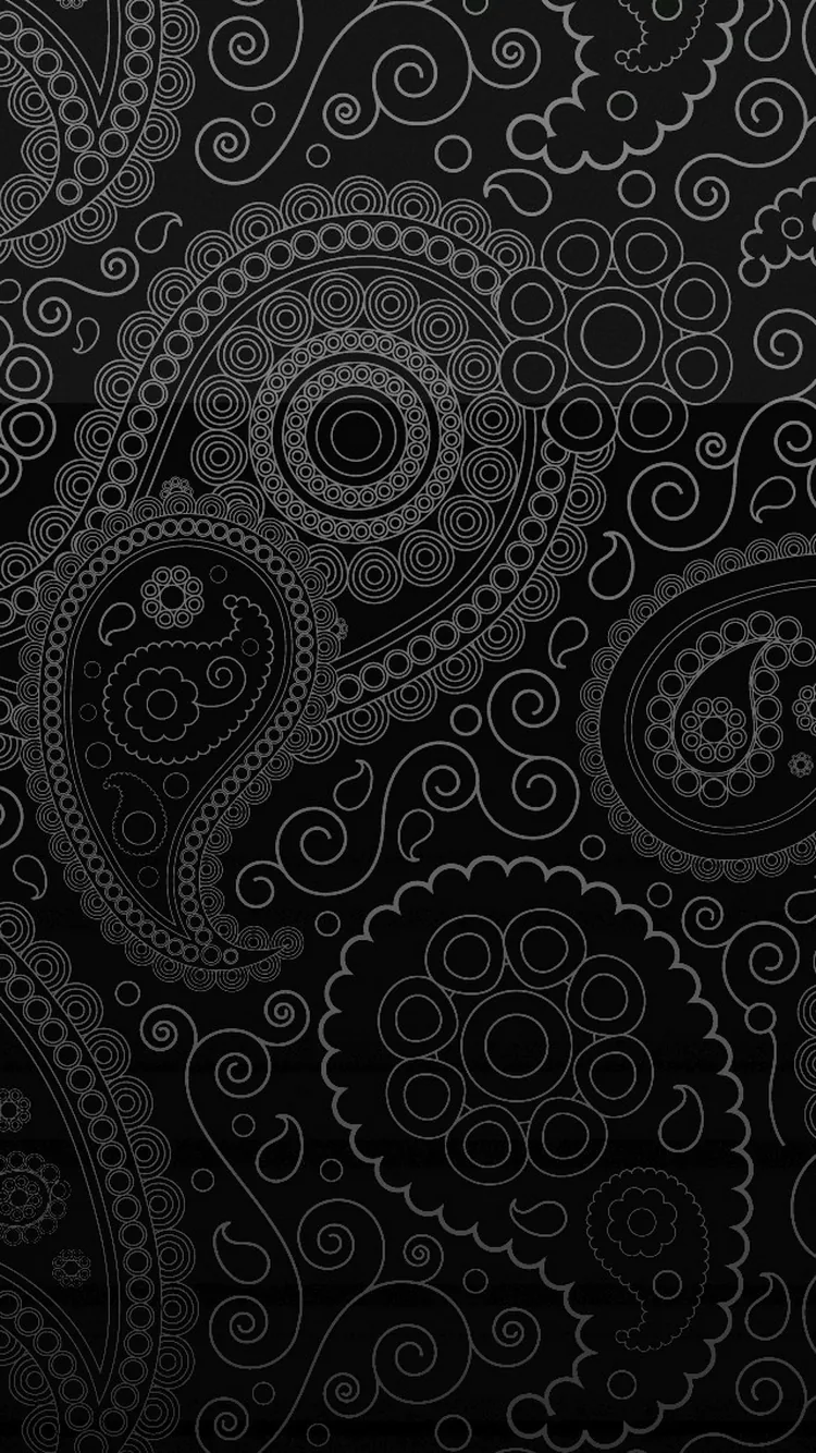 Paisley teardrops and spiral rosettes are pressed into a black surface, the raised outlines catching just enough light to separate them from the background.