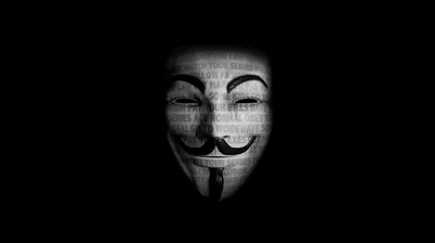 A pale mask surfaces from black with faint lines of type running across it, the edges fading into the background.