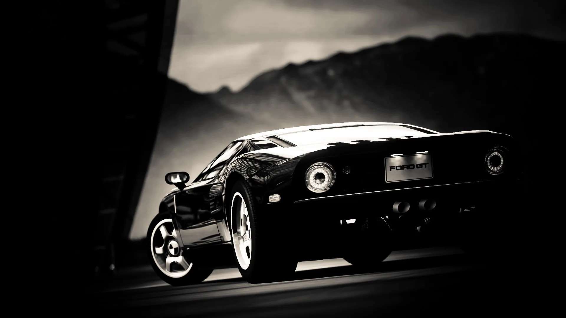 The rear three-quarter of a black sports car sits low against hills and sky, its round tail lights and rims the brightest points in a near-monochrome shot.