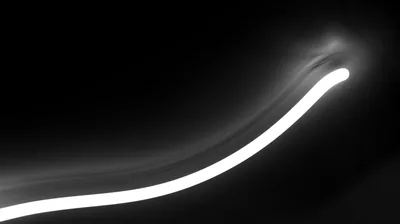 One long exposure trail bends up from the lower left and tapers off at the right, monochrome with soft haze around the brightest bend.