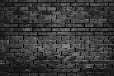 Weathered brickwork in grey and black runs edge to edge, single bricks chipped pale and the mortar lines under a flat frontal light.