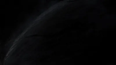 A pale edge of light curves up from the lower left across a black field, the surface reading like fur or smoke where it catches the glow.