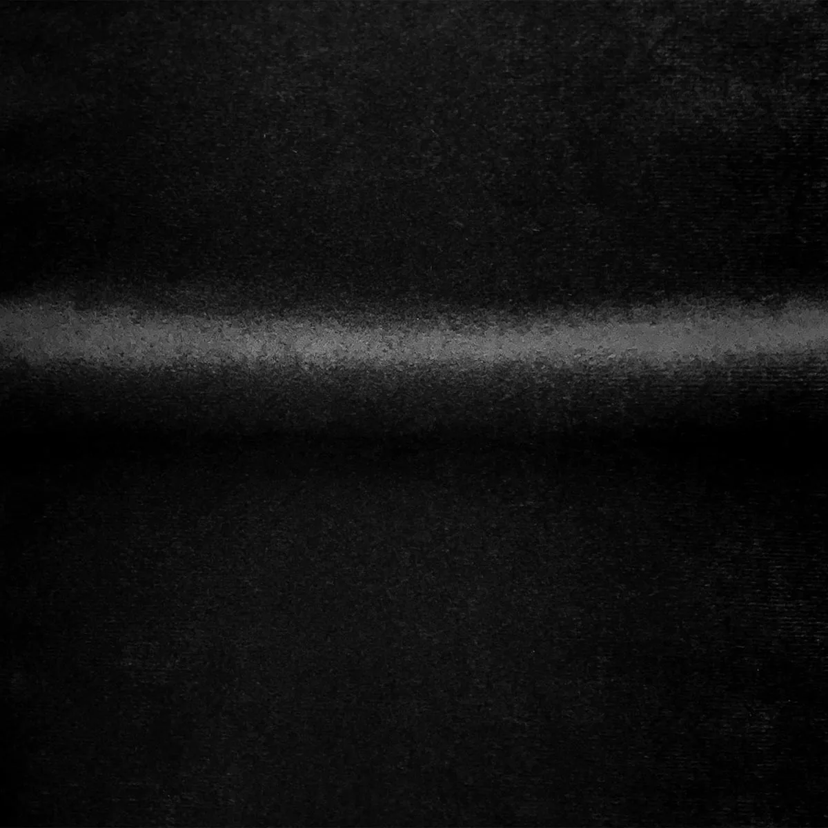 A single soft band of light runs across black velvet a third of the way down, the pile visible only where the light touches it.