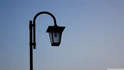 A classic lantern-style lamp post stands in silhouette against a cloudless early-evening sky, all the detail held in the left half of the frame.