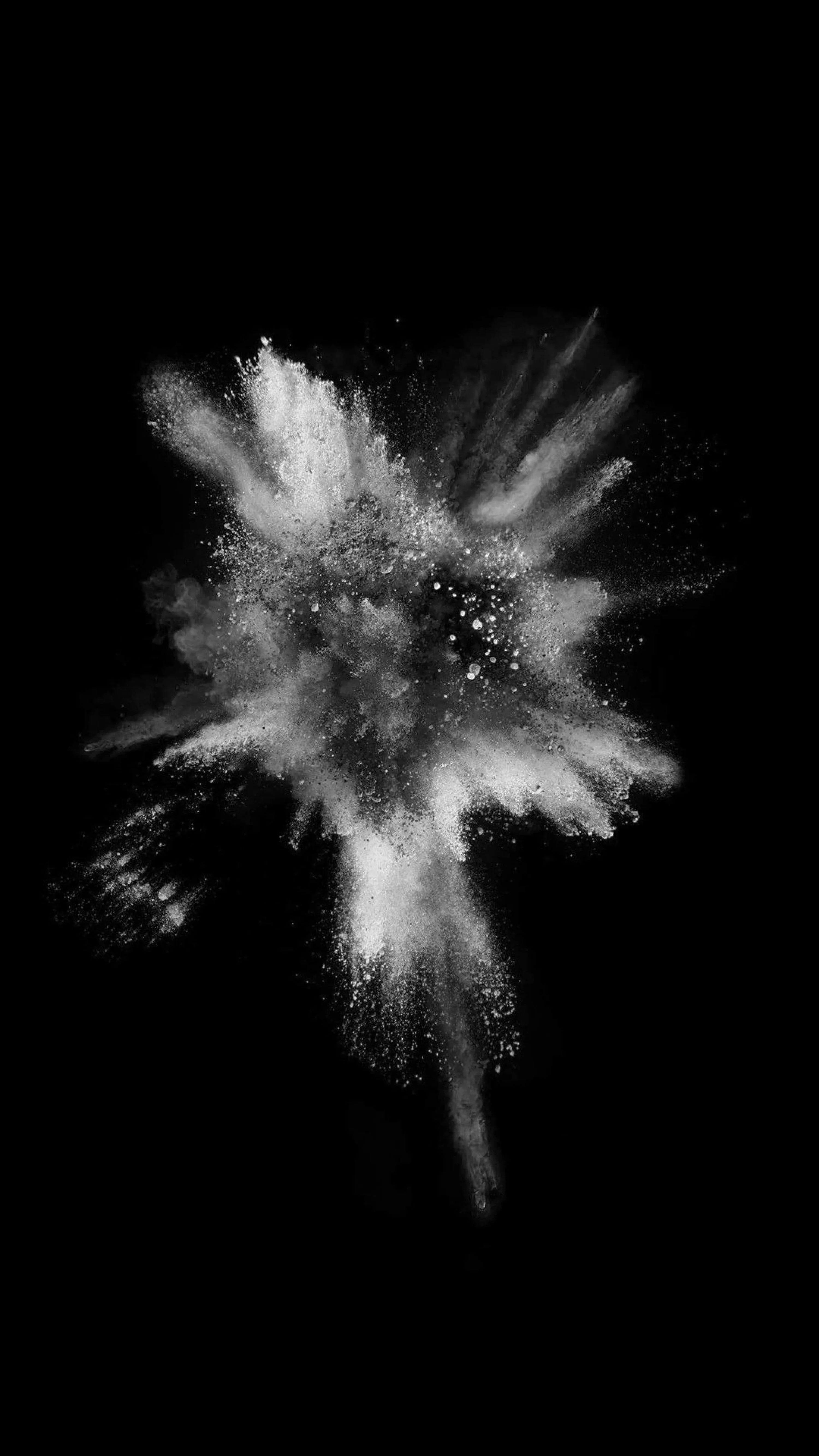 A burst of white powder frozen mid-air on solid black, the finest particles scattering to the right while the core stays dense.